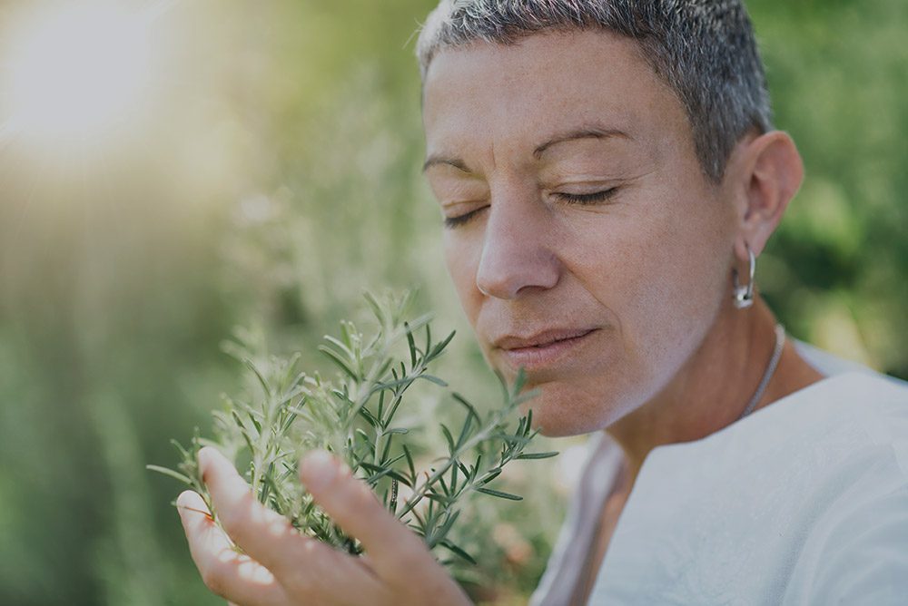 Woman with short hair smelling rosemary